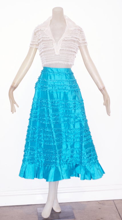 This Valentino ensemble, by Mr. Valentino, has a ruffled turquoise silk skirt and a white tulle top beaded  to give the illusion of white coral.