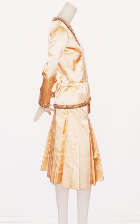 A pale peach silk Chanel haute couture ensemble from the mid 1970s.  Tunic top has gold bead embroidered trim and thin silk belt with gold beaded tassels.<br />
<br />
The beads are two tone: gold and silver and at the edges are tiny crystals.<br