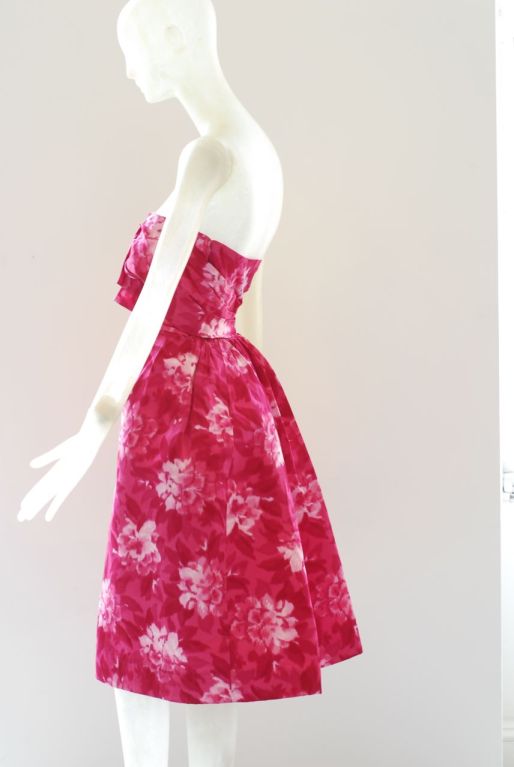 Frederick Starke started his line in the 1920s.  He designed clothes for Honor Blackman in The Avengers.  This lush pink strapless floral cocktail dress has clean straight lines in the front and a romantic back that is slightly bustled.  Dress makes