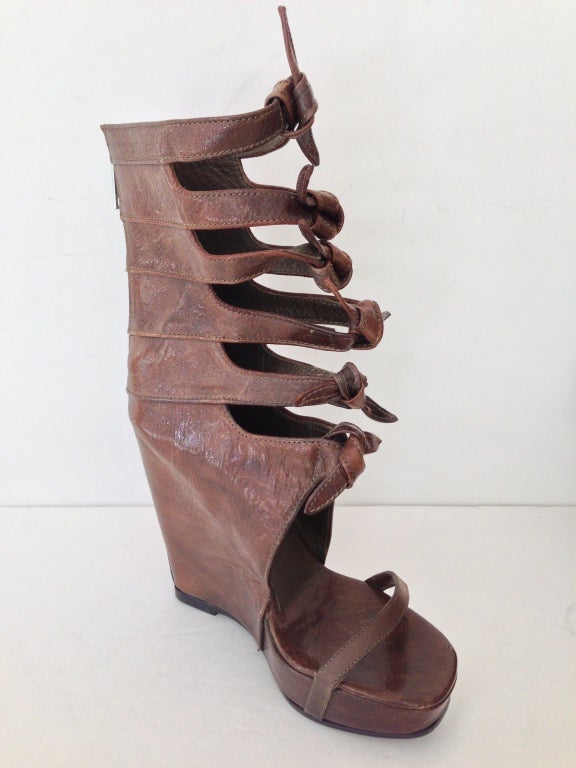 The coolest sandal/ bootie ever
6 knots are tied up the front 
Zipper in back 
Beautiful warm brown leather
Never worn, please note a few scuffs on inside sole
4 1/2