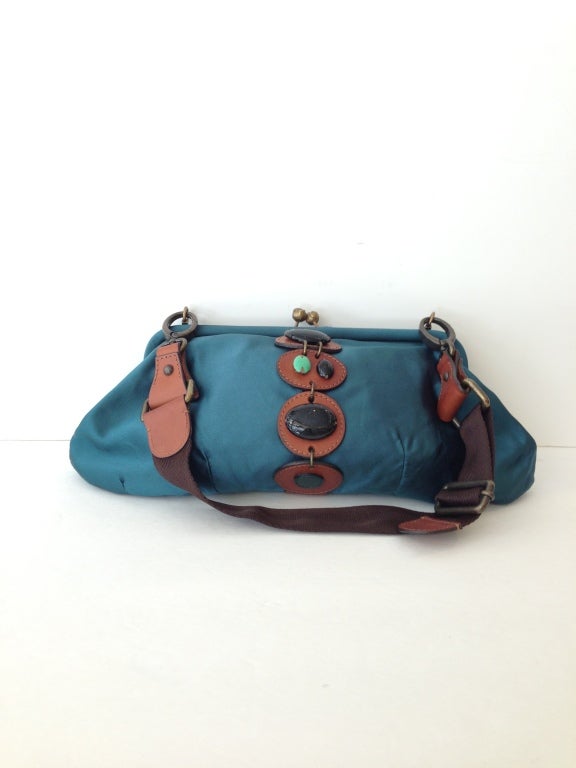Heavy silk satin bag
Four discs of brown leather as detailing with four stones mounted on top of leather
Brown nylon strap
Teal satin lining with one small open side pocket

Guaranteed authentic
All sales are final