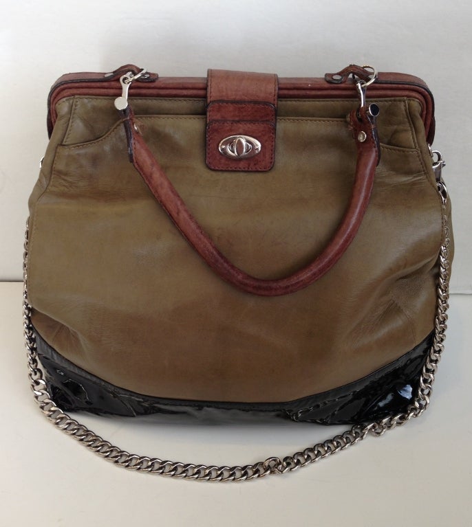 Three kinds of sumptuous leather make up this unique, versatile bag. A sturdy patent leather base gives structure and edge, while buttery soft olive and natural textured brown make up body and trim. A large front pocket closes with the silver clasp,