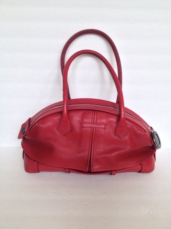 A stylish, whimsical introduction to fall. This primary red leather Gaultier bag is our favorite new way to wear a trench coat! 

We love the oversized button pull on the exposed silver zipper, and the buttons at the front which cleverly hide