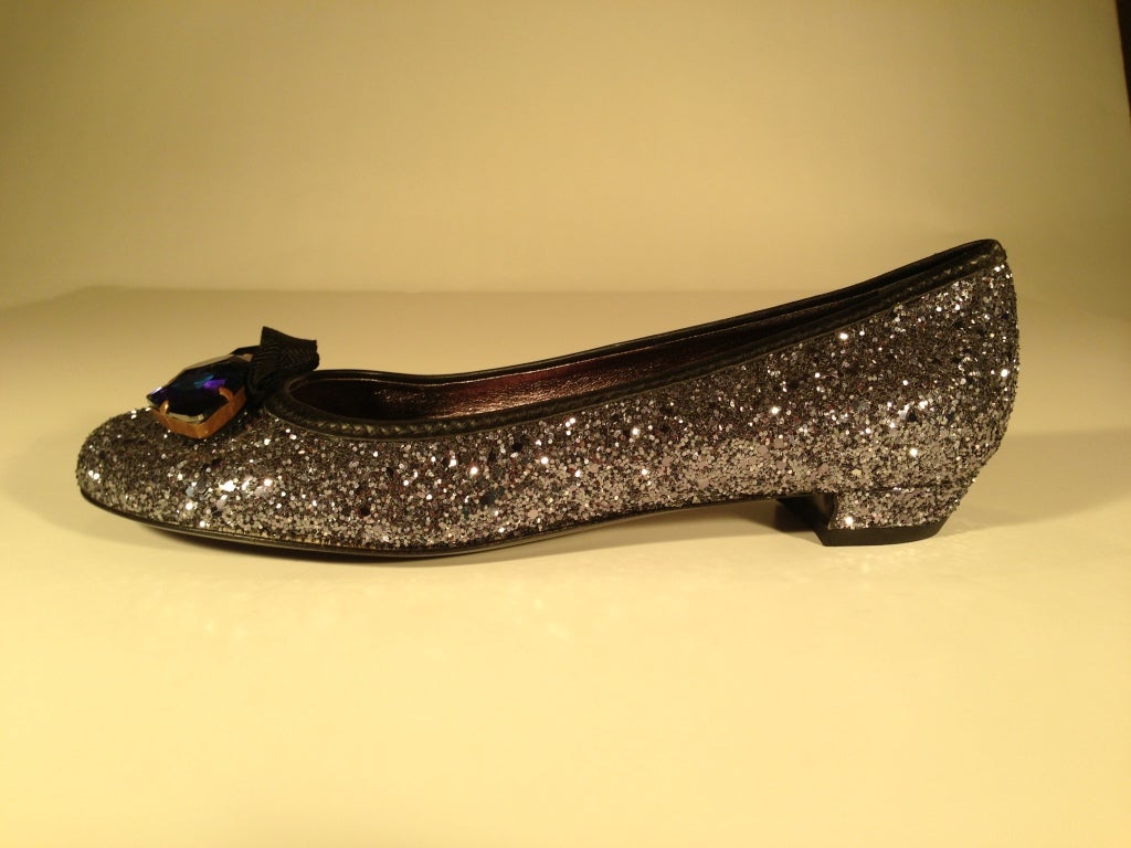 3/4 of an inch heel
These flats are definitely an attention grabber...
They are completely glittered in silver, with a tiny black bow in front. Mounted in front of the bow are three stones in aurora borealis blue, turquoise and purple.  There are