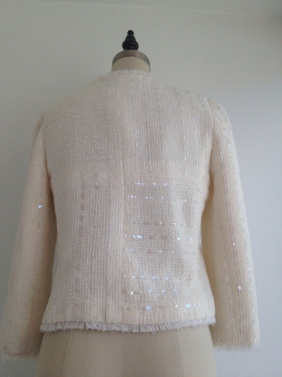 Bright as fresh snow!  

This Chanel jacket is the perfect cover up for any season.  It has 3/4 sleeves and hits at your natural waist for a flattering, feminine fit.  Clear sequins are worked into the white tweed for a crystalline effect and