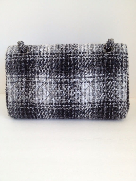 Have your winter Coco with this delightful classic tweed purse.  Black, white, gray and just a hint of metallic thread make up the the quilted tweed.  Gunmetal gray CC's grace the front flap with a twisting button for closure.  Tweed is also woven