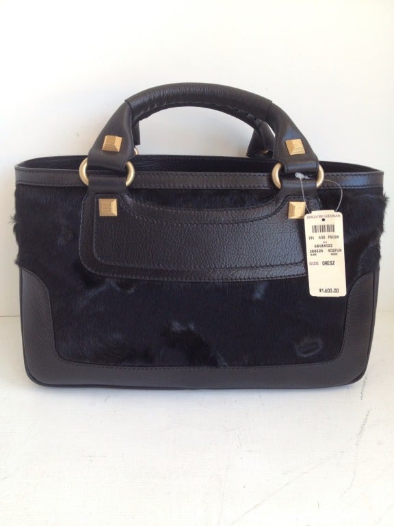 Soft black leather and even softer pony hair create this piece of arm candy.  The body is divided into two open cloth lined compartments by a large zip pocket in the center.  Two more small open pockets are found at either end.  The leather double