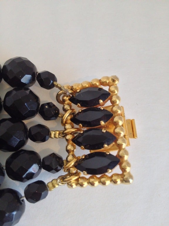 Multifaceted black beads add sparkle to your wrist.  Five strands are held together by a chunky gold clasp with additional black beads.  A great addition to any outfit, it looks beautiful over a fitted sleeve or on bare skin.