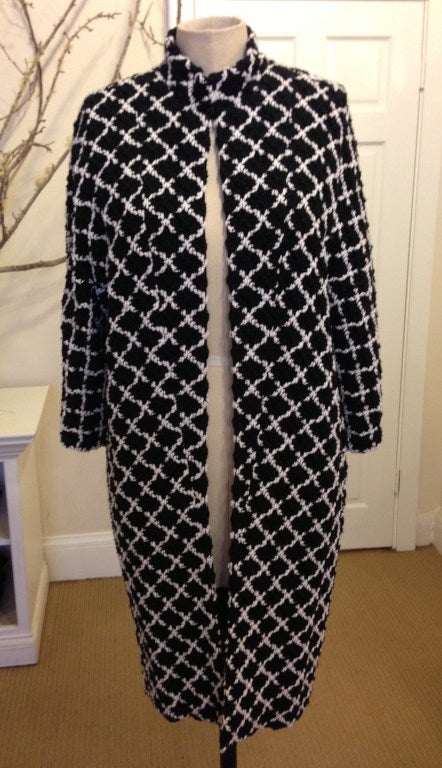 This black and white Chanel coat has a thick cotton weave in it. It has a complimentary crisscross design throughout. It's perfect for the fashionista following color trends this spring. This length can be worn dressed up or down.. There is a stand