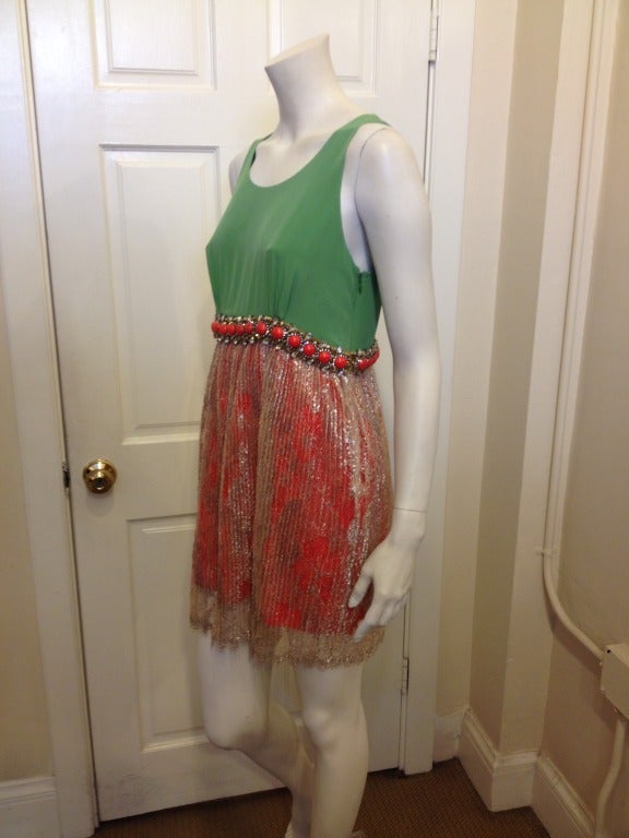 Be ready for spring in this brightly colored Balenciaga dress. The coral skirt is layered with pleated gold lace for an elegant look.  Beautiful green silk makes up the top and an ornate beaded waist ties everything together.  Golden thread is