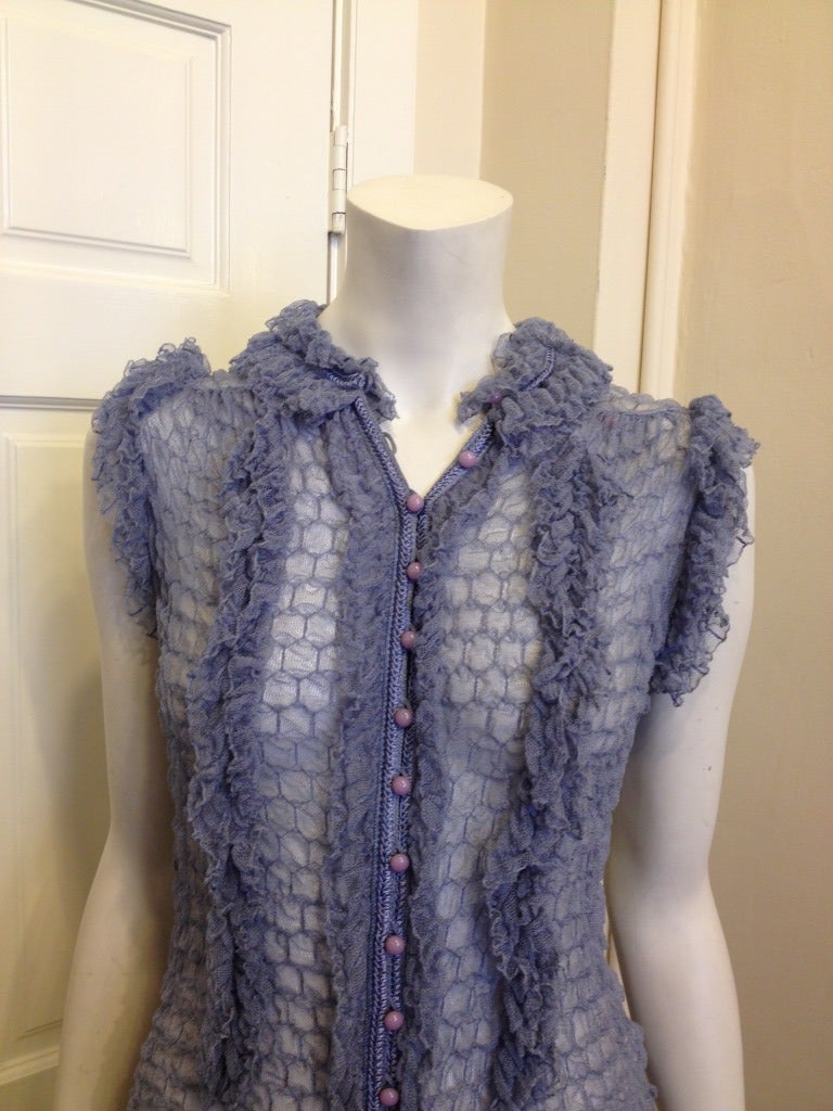 Fun and flirty, this blouse is the perfect topper for any outfit!  Gorgeous dusty blue silk has ruffles around the neck and down the front, plus a horizontal ruffle across the shoulders.  Small lavender buttons provide closure.  Play up your
