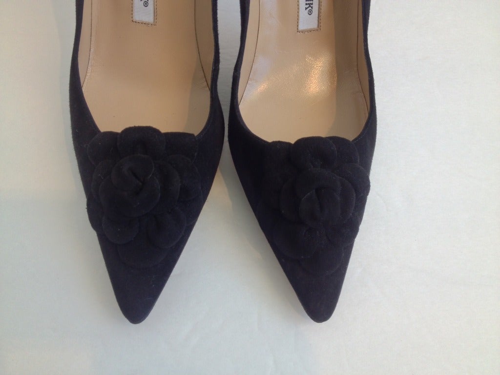 Add these beautiful black Manolo Blahnik heels to your collection! The suede adds texture to the shoe, and gives a softer look to your outfit while the pointed toe makes your legs look long and lean. There is also a lovely suede flower on the toe