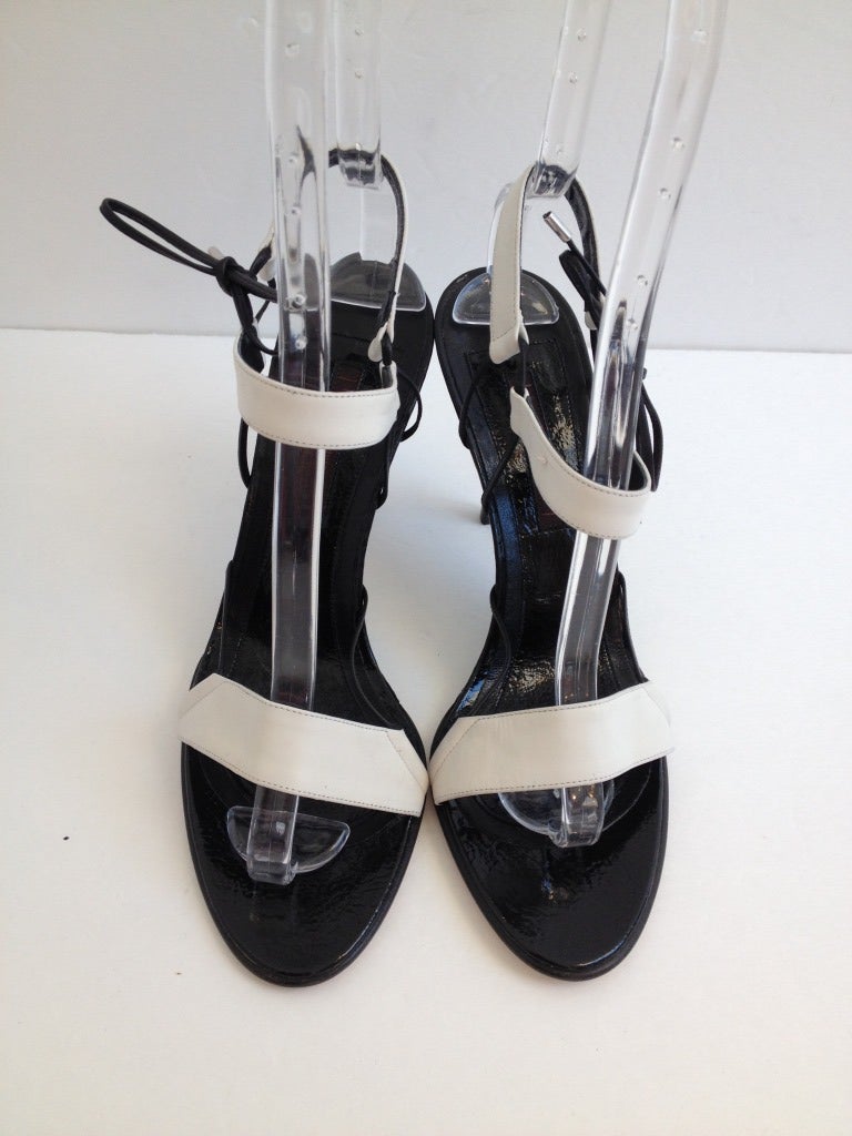 Narciso Rodriguez is known for making stunning yet simple pieces, and these shoes stay true to that idea. These sandals have a black base with 3 white straps; one across the toes, one across the vamp, and one behind the heel. The two upper straps