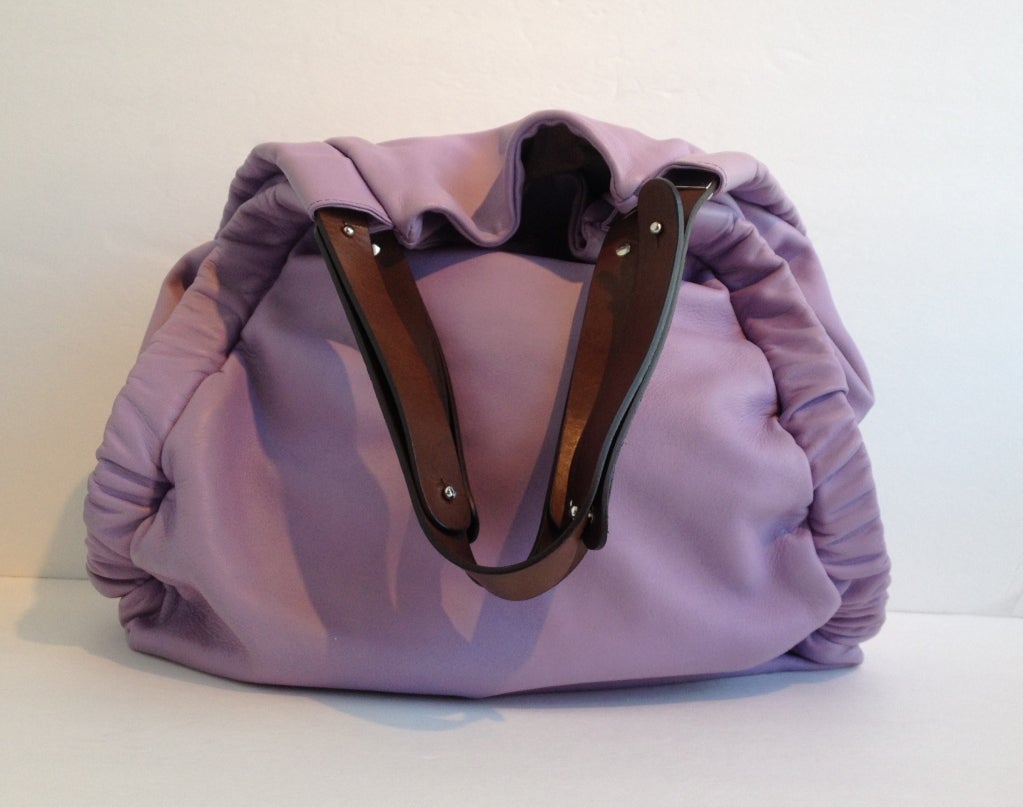 Spring is in the air and on your shoulder with this lavender leather purse.  The slouchy design is perfect for toting around all your belongings and the roomy interior should have no problem fitting them all.  The top closes with a tan leather strap