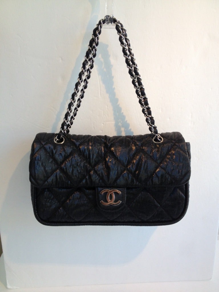 This Chanel bag has everything you love about the classic style, but in a lightweight, treated fabric!  The shiny, black nylon is quilted and closes with a magnetic clasp.  The silver chain is woven with the same material as the purse.  Inside is
