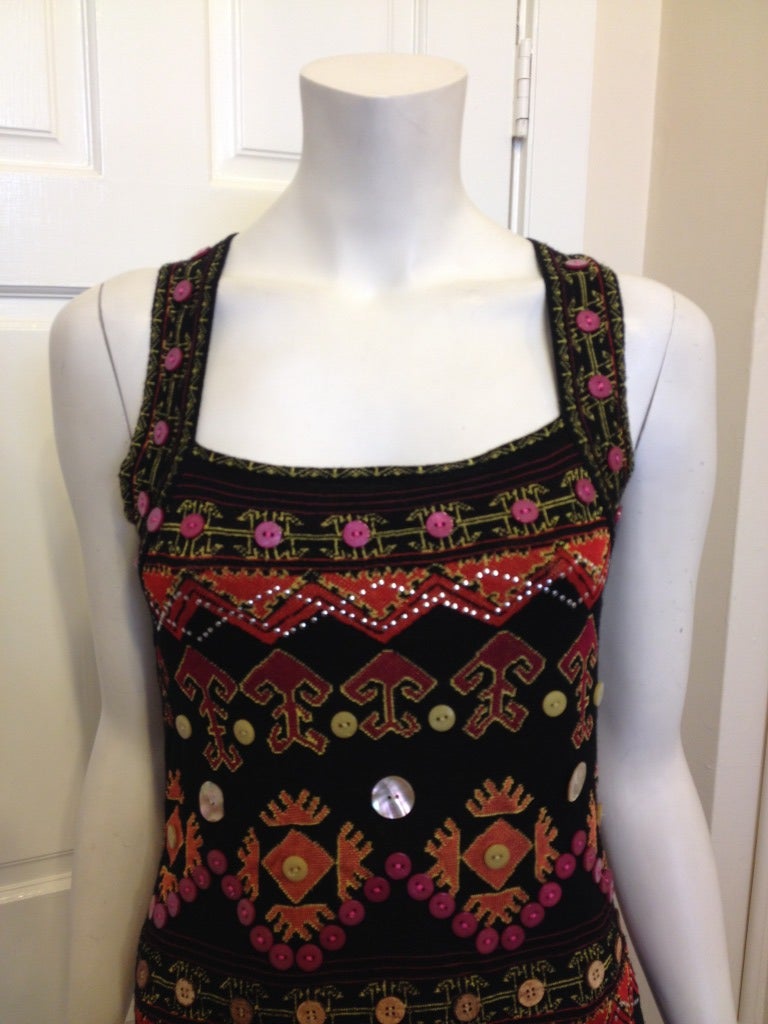 Looking for an amazing piece to wear this summer? Try this detailed top by Christian Dior! This black top has an intricate design in orange, yellow and red pattern.  Buttons of different sizes and colors as well as small silver metal studs are