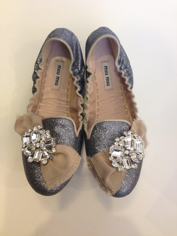 A picture is worth a thousand words...
~ silver very fine glitter, bordered with beige trim around the shoe
~ Grosgrain ribbon with an elaborate crystal brooch on each shoe

Shoes come with box.
All sales are final.