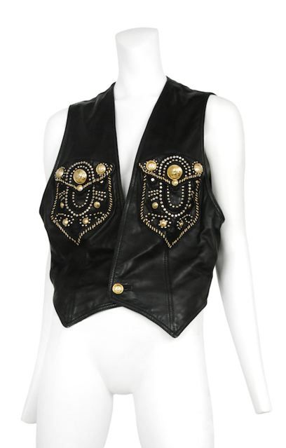 Black lambskin leather 2pc ensemble. Both pieces are heavily decorated with gold studs and Medusa head tacks. The shorts have zip fly and button front closure with attached buckled belt.