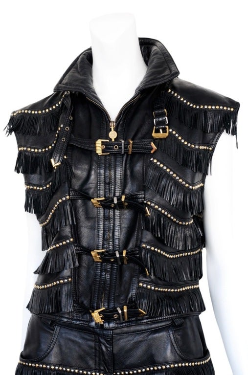 5 pocket leather pants and sleeveless jacket. Both pieces are covered with soft fringe, gold studs and Rhinestones. The vest is further embellished with gold buckle closures.