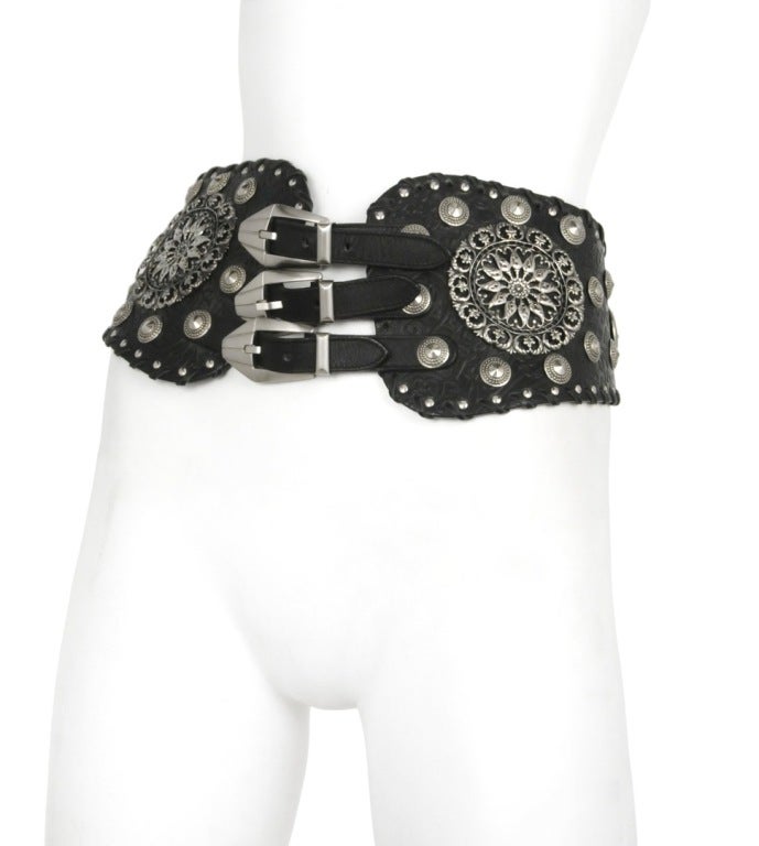 Black leather embossed waist/hip belt.  3 buckle closure at front and one buckle closure at back. Large Medallions on each with stud a tack detail through out.