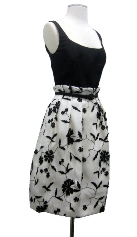 Cute but elegant cocktail dress by Oscar De La renta.  Solid black top with attached woven floral applique pleated skirt and belted at waist.

- Bust 17
