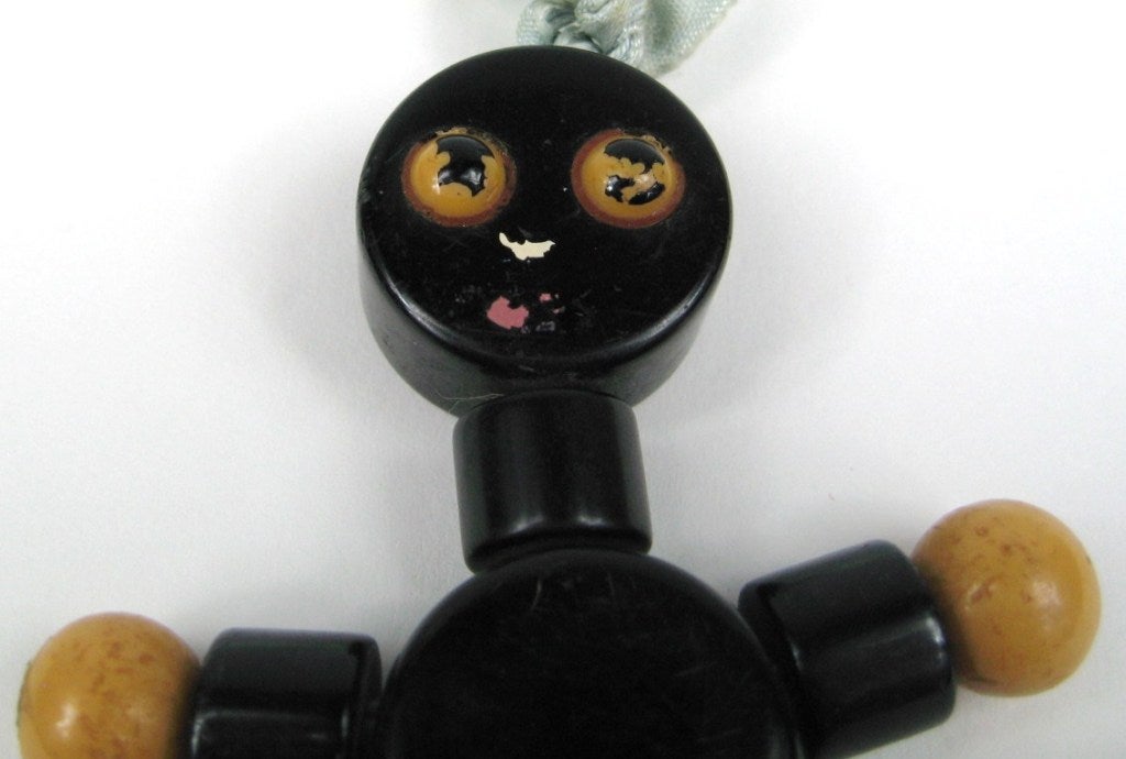 Adorable Bakelite Pendant Crib Toy it Measures 4 inches top to bottom. The Body is black with orange, yellow and butterscotch. Some minor wear to the face, doesn't detract gives it character. Be sure to check our store front for more fabulous pieces