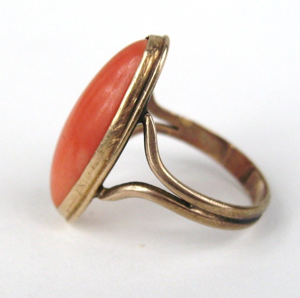 Délicat cabochon de corail allongé serti à la lunette en or 10K. La bague est une taille 4.5 et peut être ajustée par nous ou votre bijoutier. Le corail mesure environ 0,75