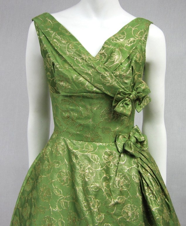 Stunning 1950's cocktail dress by Will Steinman

Subtle gold Lame running through this Steinman piece. Backed fabric, with tulle lining. Bows adorn the side of the bust, waist and then feature a gathered side. Inverted pleat on the back. Clip