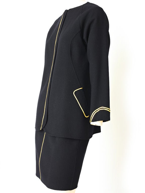 Geoffrey Beene 2 piece dinner ensemble. Collarless long fitted jacket in a wool crepe with straight fitted skirt. Jacket and skirt has gold piping detail.