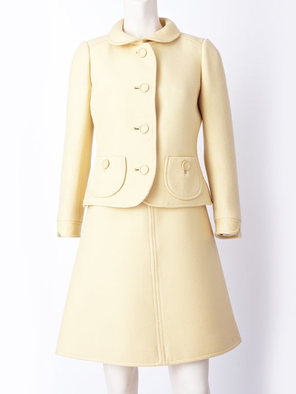 Courreges, pale peach tone dress and jacket ensemble. Dress is jeweled neckline, sleeveless, a line shape with a back half belt detail. Jacket falls at the hip with 2 rounded pockets, with a button detail. Small rounded collar.