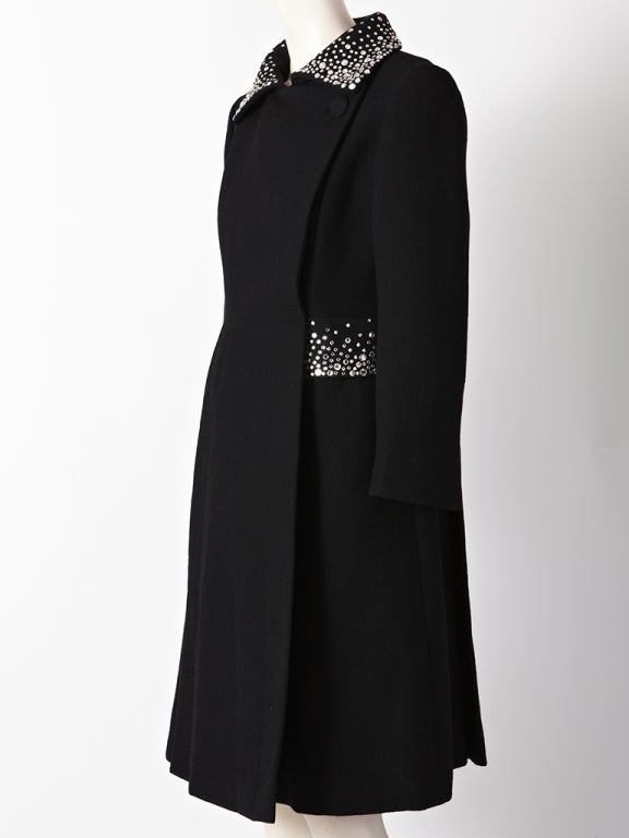 Pauline Trigere, black, wool crepe, evening coat with diamante detail on collar and hip pockets. Coat has side closures with a fitted silhouette that goes into an A line shape.