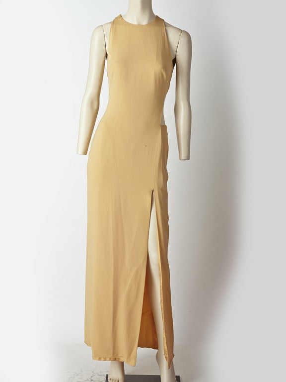 Gianni Versce, apricot tone, crepe, fitted gown with cut out side and back detail. High front slit and halter shape sleeve detail.