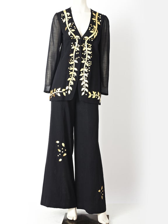 Pauline Trigere, cotton voile, jacket and pant ensemble.
Jacket is semi fitted, hip length with a fitted sleeve and hook and eye front closure. Jacket is embellished with gold lame appliques. Pant is bell bottom, with scattered, gold leather