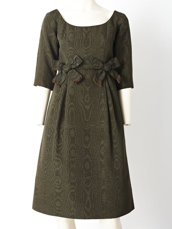 Olive green, moire, empire waist, cocktail dress with a scoop neck, 3/4 sleeves and bow detail under the bust. label reads,
