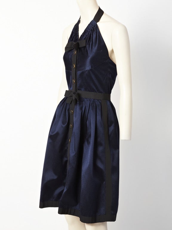 Chanel, midnight blue, hammered satin, halter dress. Dress has black gross grain ribbon trim down the the front of the dress, waist, side seams and hem. There is a bow made of the same gross grain at the center waist and at the neckline. Dress