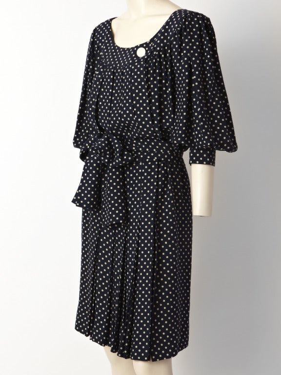 Yves Saint Laurent, navy and ivory, polka dot, satin back crepe dress with a smock like bodice and sleeves,  self belt, stitched down pleats at the hip and side front closure.