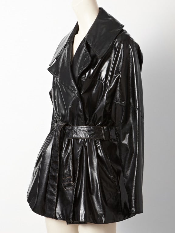 Alaia, black patent, belted, double breasted, short, trench with large notched collar, side pockets and raglan sleeve detail.