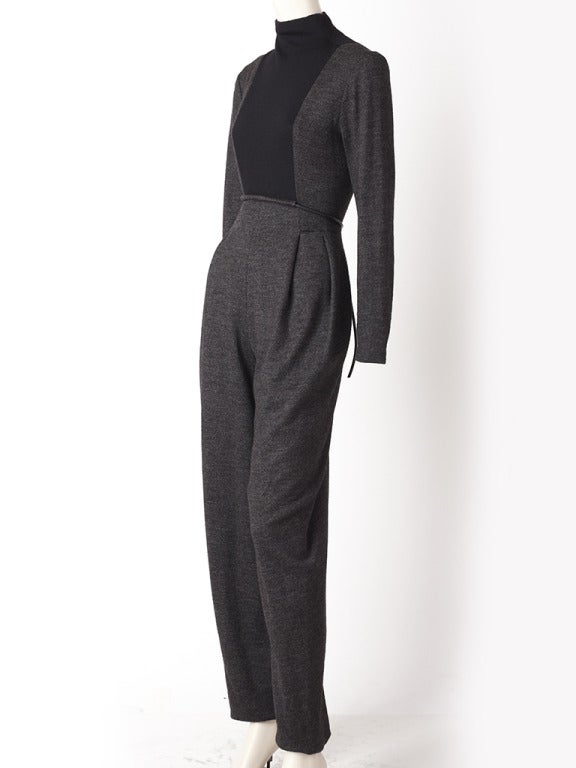 Goeffrey Beene, charcoal,and black wool knit jumpsuit. Body of the dress is charcoal grey, with a black panel inserted at the bodice with a funnel neck. There is a tubular leather belt that loops through the empire waist bodice.