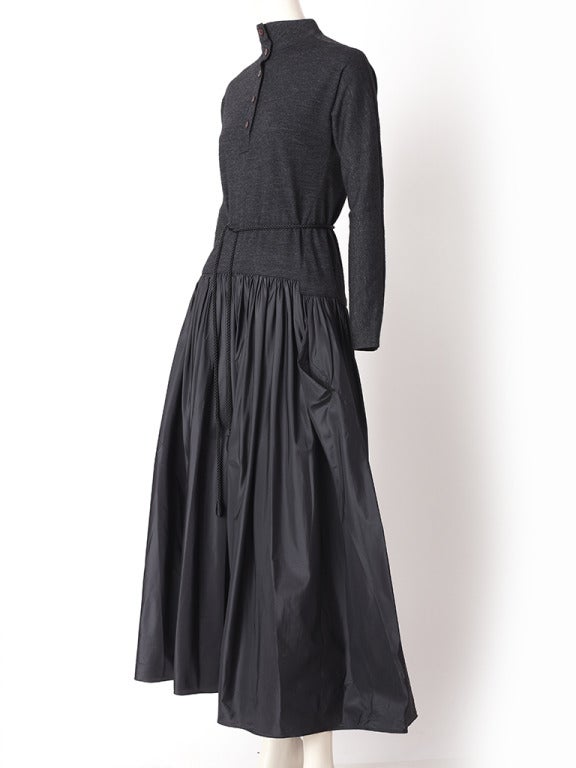 Geoffrey Beene, wool jersey and taffeta, dropped waist dress.
Bodice is slightly fitted, charcoal grey, wool jersey with long sleeves and button up front and a high turtle neck. Skirt is gathered, silk, tissue taffeta, tea length, with pockets.