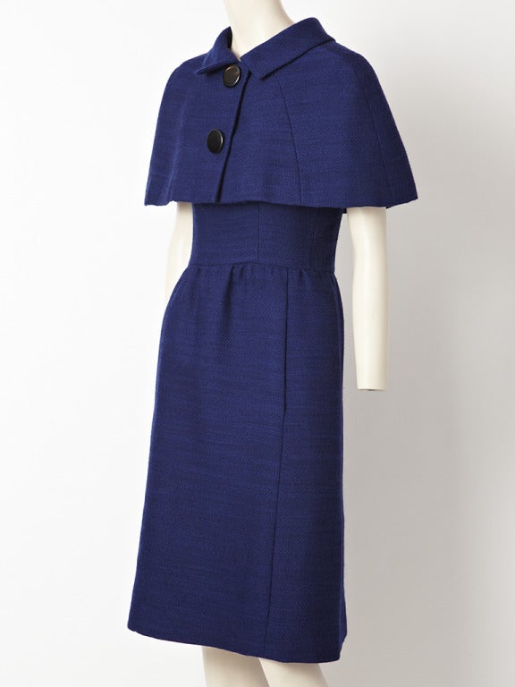 Norman Norell navy blue, wool day dress with matching Capelet. Dress has a fitted bodice with short sleeves and a gathered skirt. Matching Capelet fits snuggly over the shoulders and buttons down the front.