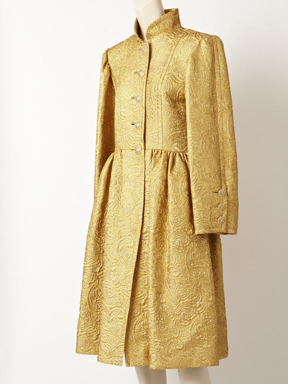YSL, Rive Gauche, rich, gold brocade, evening coat and matching skirt ensemble. Coat has a stand up mandarin collar,slightly fitted princess line bodice, with a dropped gathered waist.. Sleeves are wide. Coat is embellished with beautiful diamente