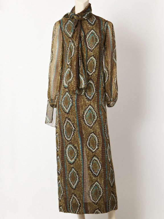Pauline Trigere, chiffon, long sheer, sleeve, jeweled neckline, long shift of an abstract, reptile print in shades of olive, brown, and touches of turquoise.
Comes with sash that can be worn as a belt or scarf at the neck. Label missing, but
