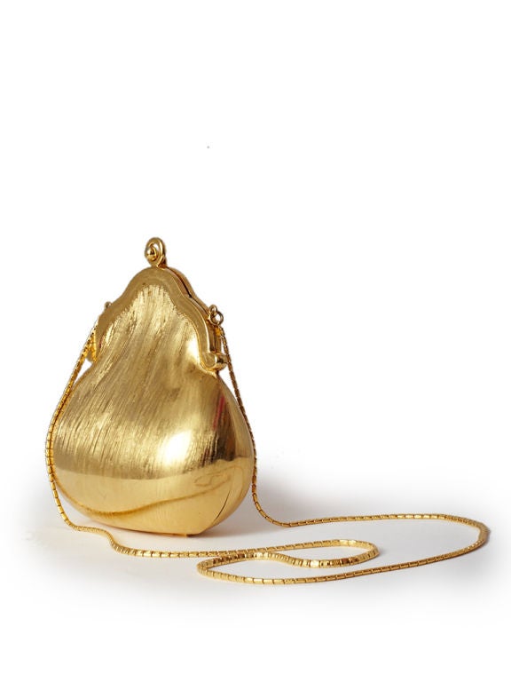 Small Judith Leiber hard gold toned minaudiere with gold chain<br />
shoulder strap. Interior is gold tone  kid leather.