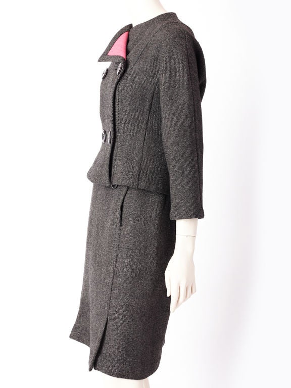Pauline Trigere double face wool suit. Jacket and skirt are a gray tweed wool with a pink wool lining. Jacket is double breated, no collar slightly fitted at the waist and ends at the hip. Skirt has two big buttons that 