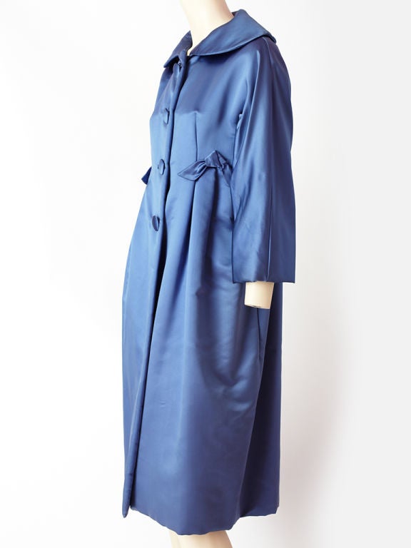 Ben Zuckerman duchess satin, Perriwinkle blue, evening coat.Details include,<br />
rounded collar and slight nipping at the waist line with bow embellishments at the sides.