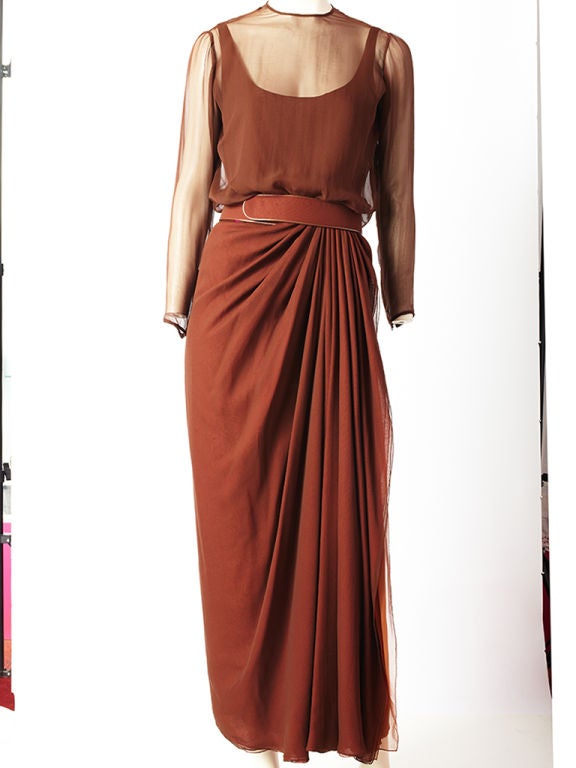 Galanos, rust toned, chiffon, long sleeve evening gown with multiple layers of chiffon in various tones of brown and beige.<br />
Sheer neckline and sleeves with matching belt and a draped panel at the left side of the waist flowing down to the hem.