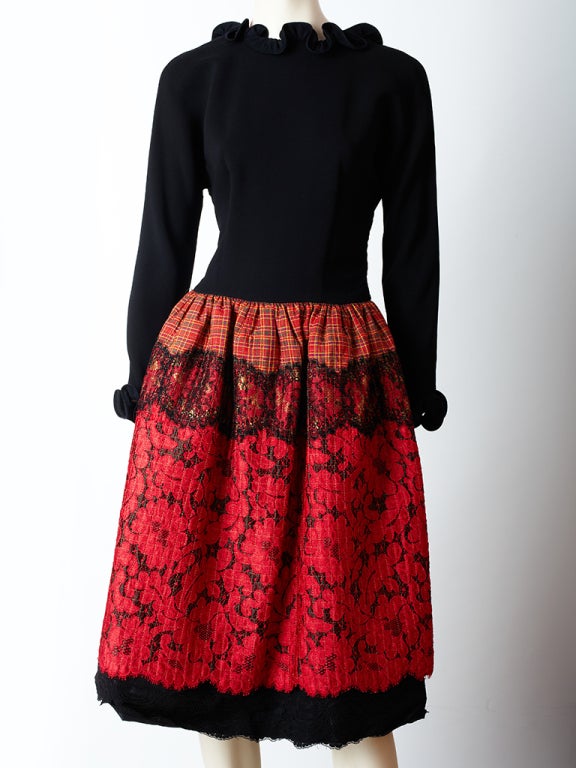 Geoffrey Beene, red and black whimsical cocktail dress. Dress has a fitted jersey bodice that ends at the hip with an open back and a ruffle neckline and cuff. Skirt starts at the hip, is quilted and is a made of a patchwork of fabrics which