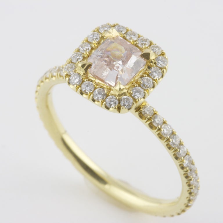 Radiant cut GIA fancy brownish, pink diamond weighing 0.64 carats. Surrounded by 50  round cut clean, white diamonds weighing approximately 1.00 carat. The hand made ring is 18k gold.

Ring size: 6