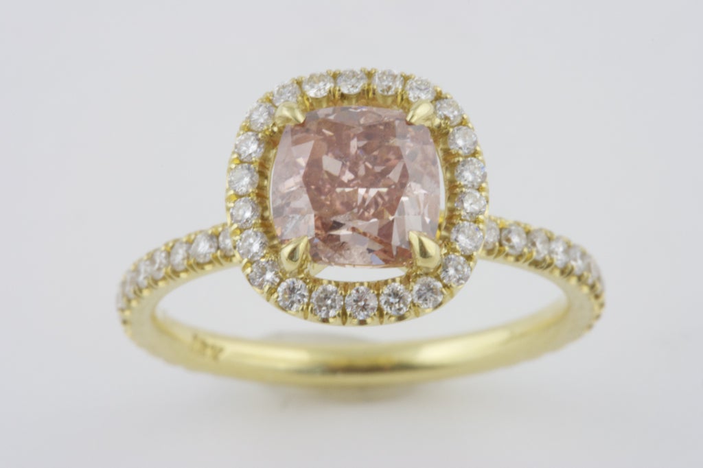 Radiant cut Pink Diamond of 1.62 carats. The GIA color certificate states the color as being  Fancy, Brownish, Orangey Pink. The 18k gold ring has 54 round brilliant diamonds surrounding the center stone. While the GIA certificate states it is