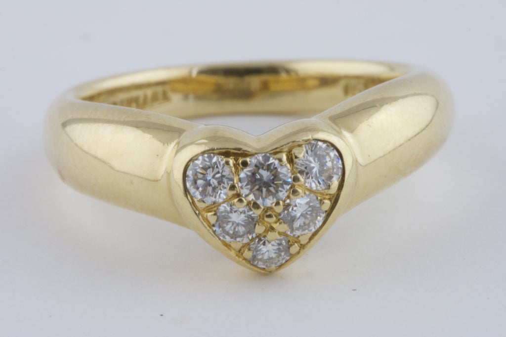 Lovely 18k gold ring, set with 6 colorless diamonds (.30 carats) in the shape of a heart. Made by Tiffany & Co. 

Ring size: 5.5

Tiffany & Co. is a multinational luxury jewelry and silverware corporation, with headquarters in New York City.